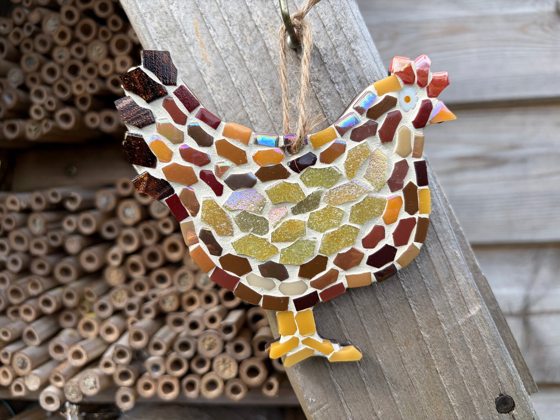 Handcrafted mosaic hen wall hanging in earthy brown, amber and olive green glass tiles with iridescent shimmer and natural twine loop