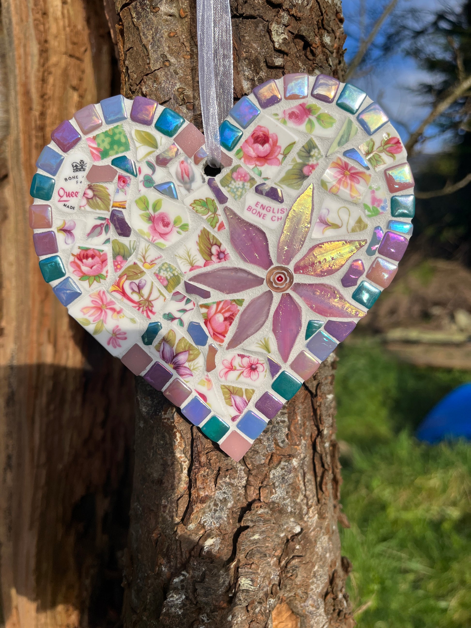 Close-up of Queen's bone china rose mosaic heart showing iridescent tile border and purple glass flower centrepiece