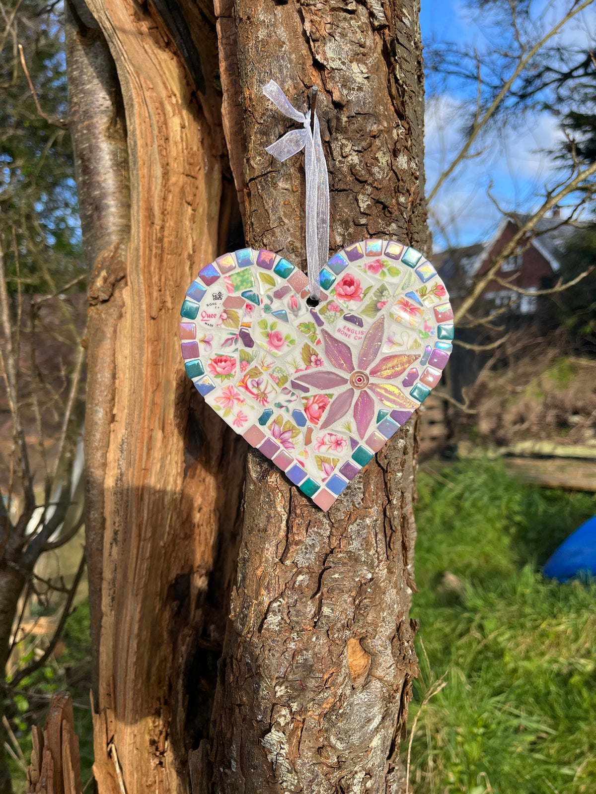 Side view of Queen's bone china rose mosaic heart hung on a tree showing organza ribbon